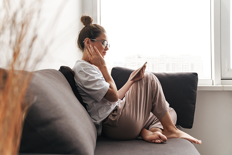 Young woman sitting on the couch looking at her phone